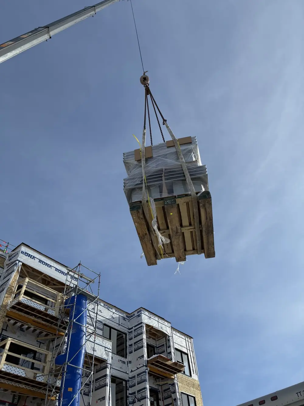 Palette de ventilateurs surdimensionnés levée à la grue vers un chantier